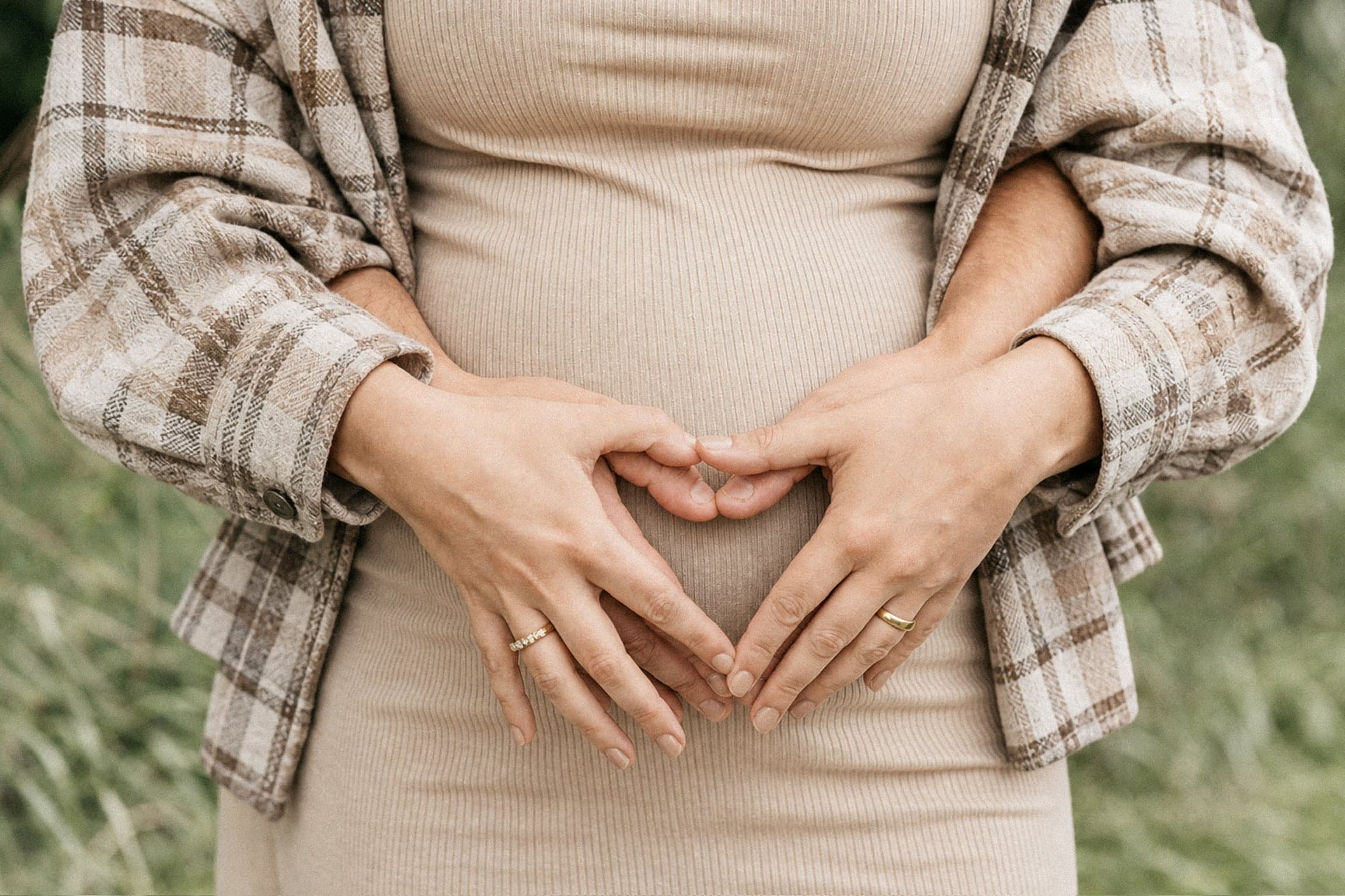 Werdende Eltern formen mit ihren Händen ein Herz auf dem Babybauch