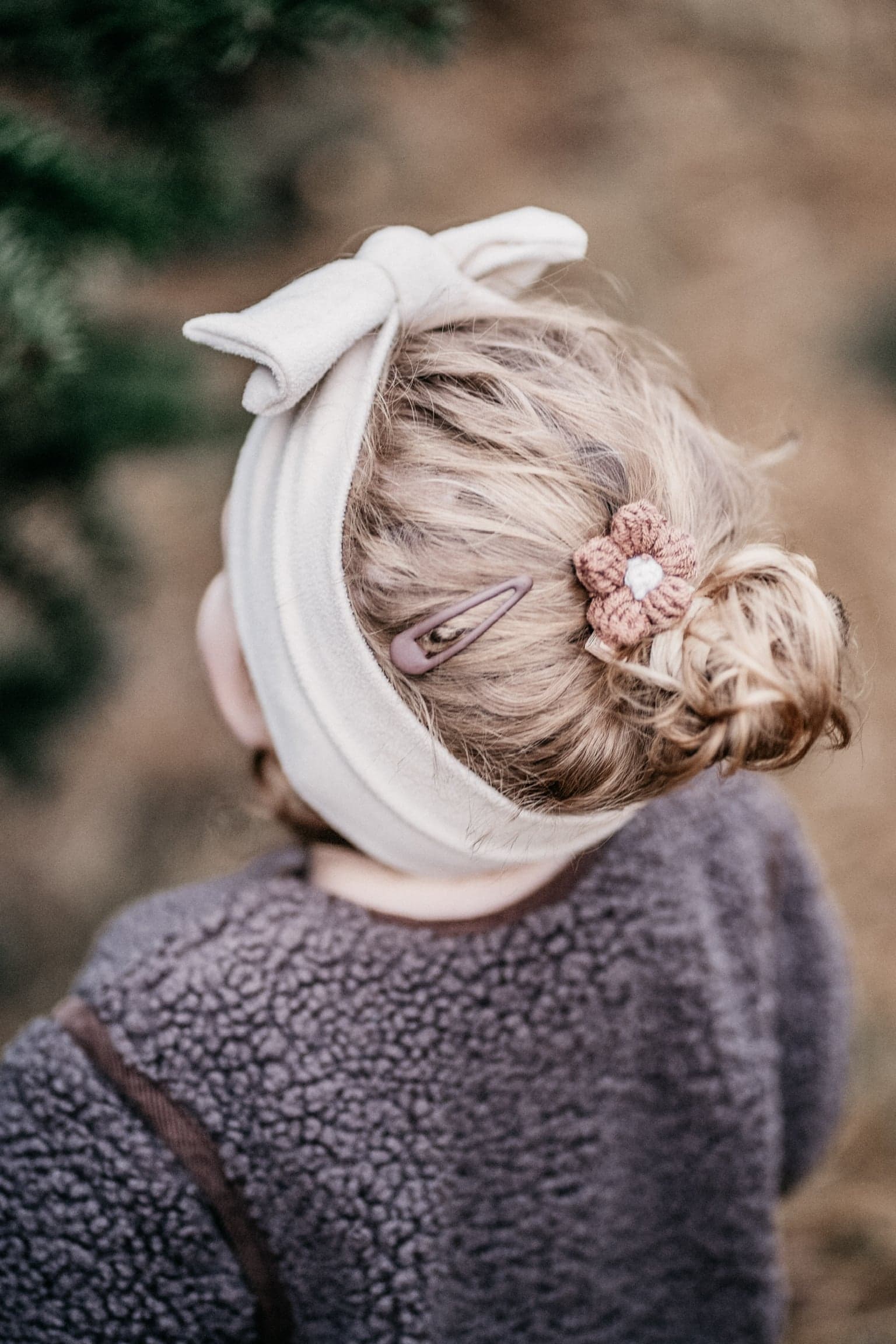 Geflochtenes Kinderhaar mit Haarband und Blütenspange, von hinten fotografiert