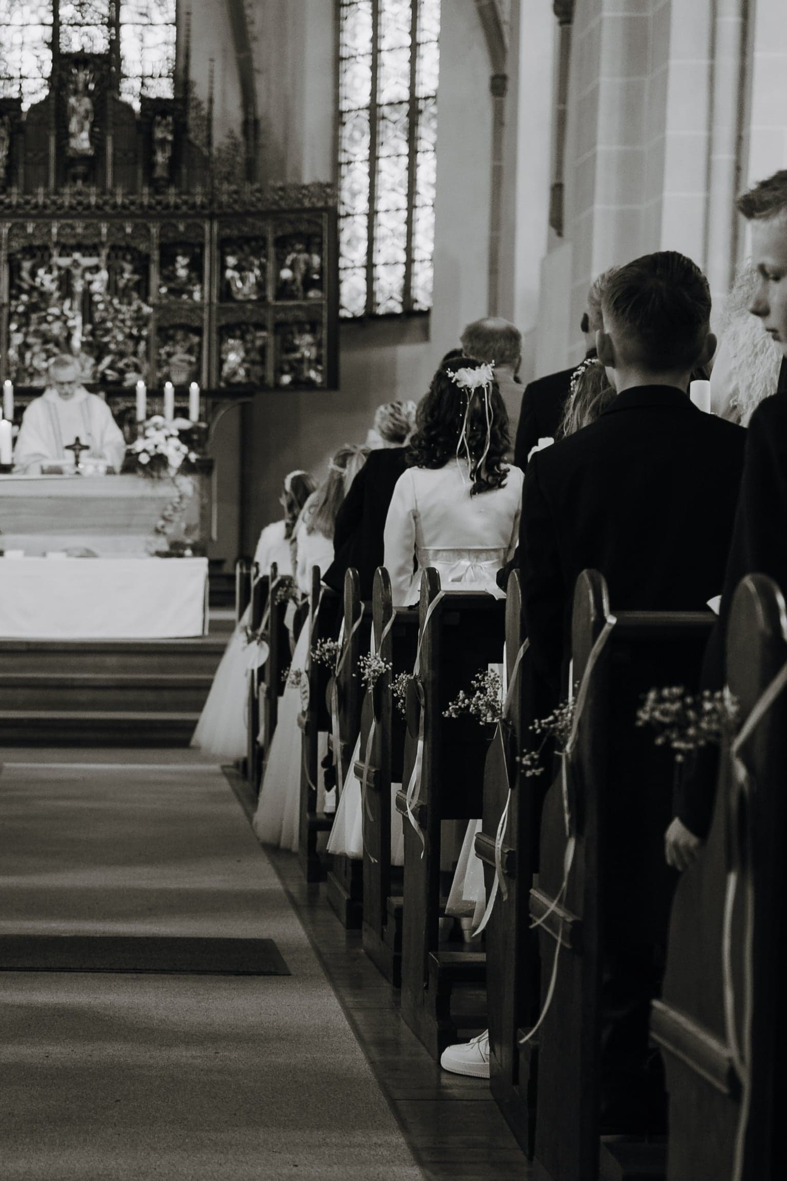 Blick durch das Kirchenschiff auf den Altar, Kommunionkinder in den Bänken, in Schwarzweiß