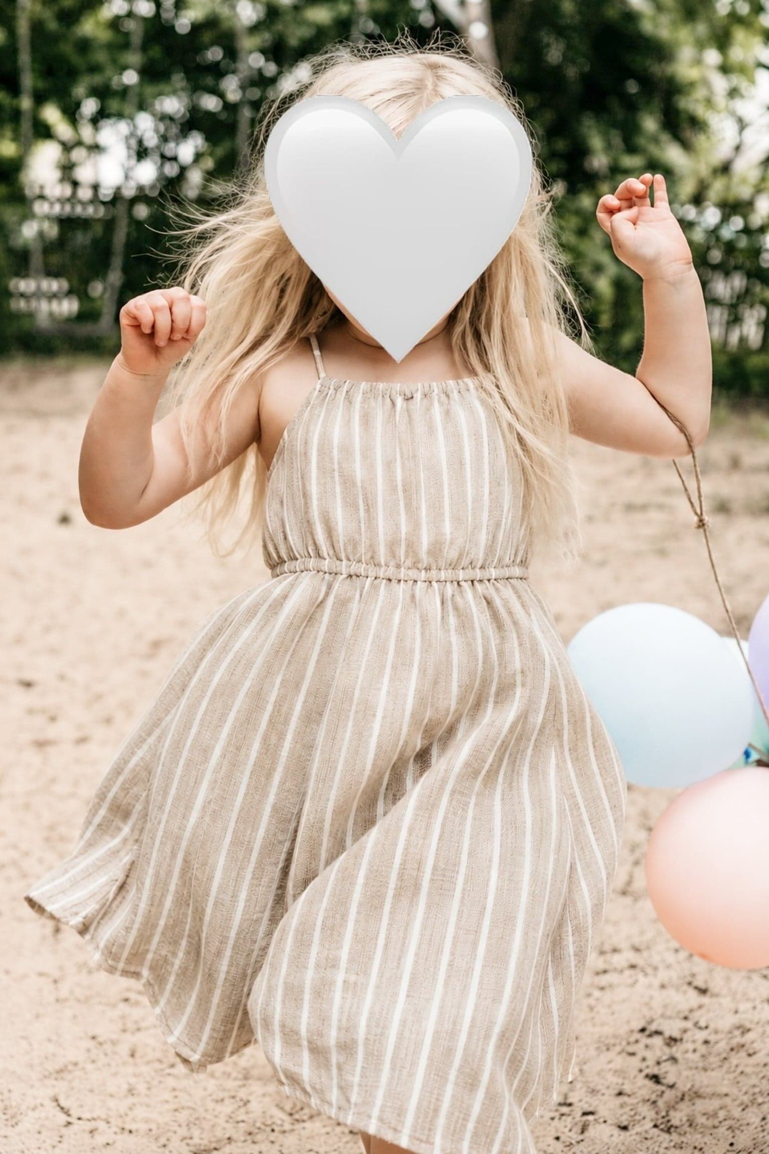 Mädchen im gestreiften Kleid mit Luftballons im Sommer