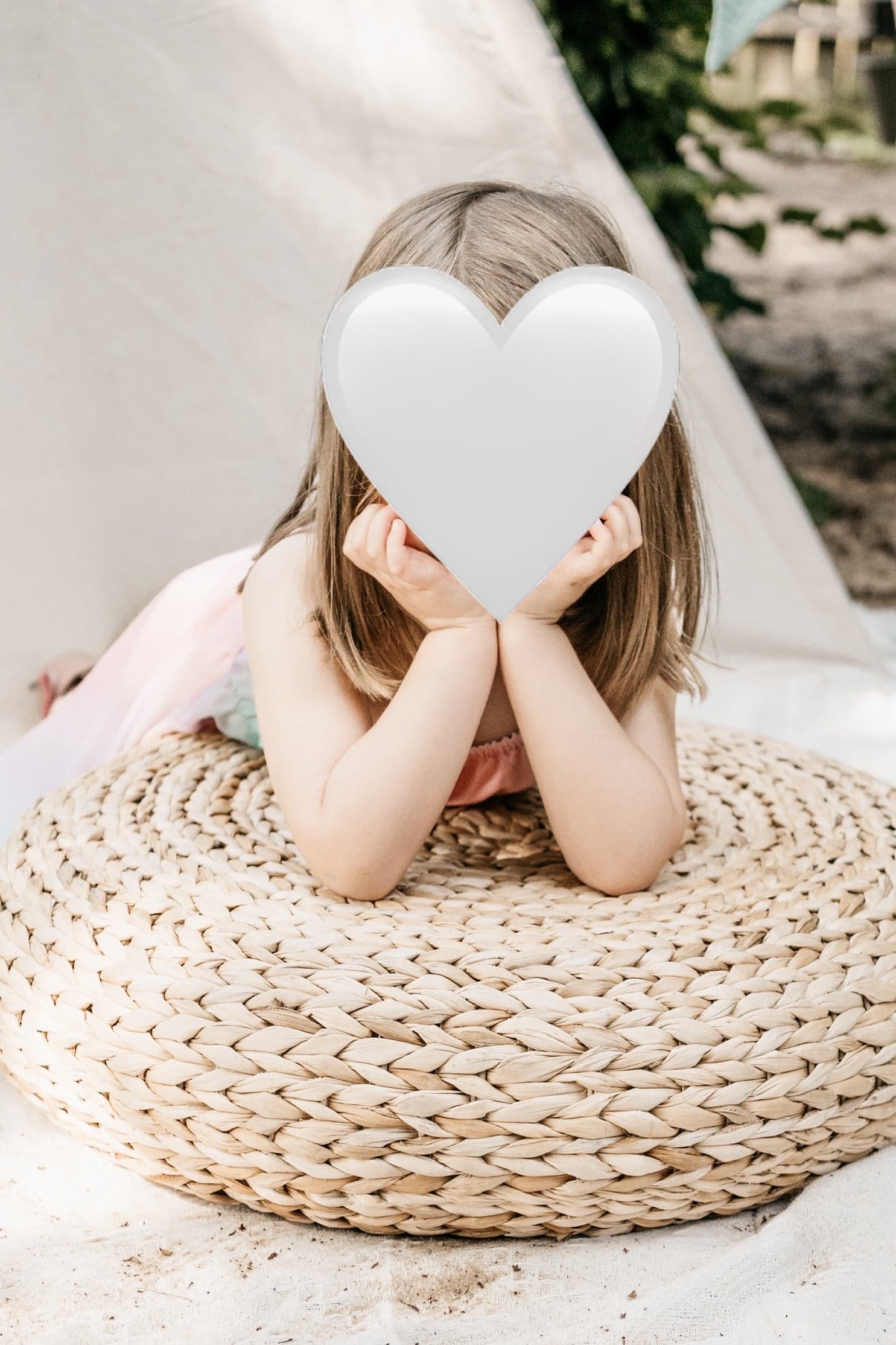 Mädchen stützt sich auf einen geflochtenen Sitzpouf vor einem Tipi